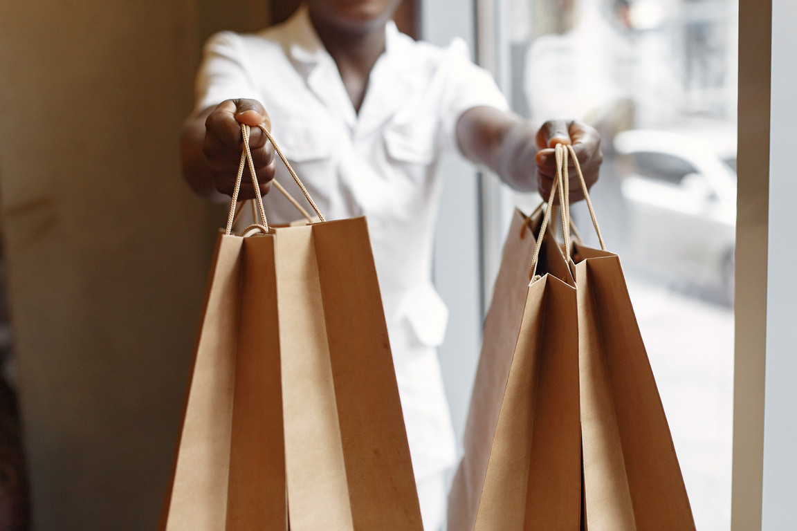 Crop seller passing purchases in paper shopping bags